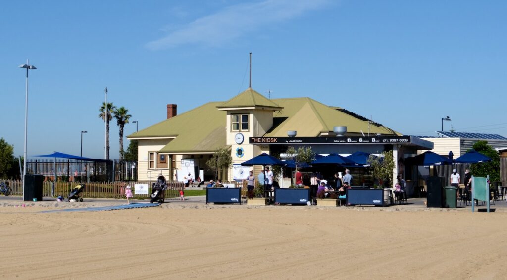a photo of a cafe with a green roof by a beach